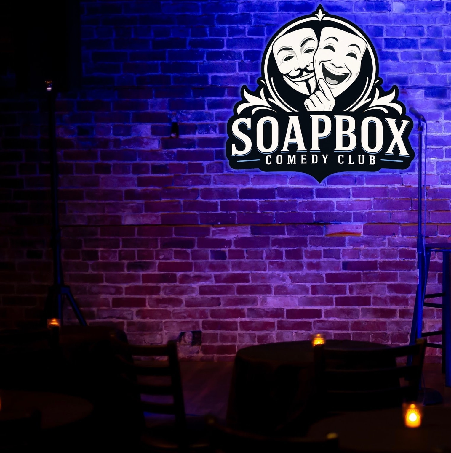 Soapbox Comedy Club neon sign on brick wall